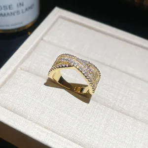 Détail d'une bague dorée croisée en forme de X avec pavé de pierres en zircone
