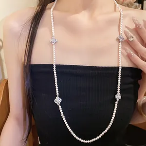 Detailed view of elegant pearl necklace with zircon flower motifs worn by a model