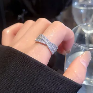 Gros plan d'une bague croisée en X scintillante avec pavé de pierres au doigt.