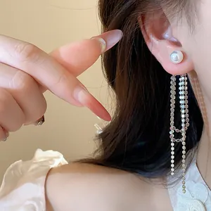 Dettaglio di eleganti orecchini a nappa lunghi in argento con perla sulla modella.