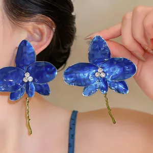 Close-up of large blue flower earrings with rhinestone center and enamel finish