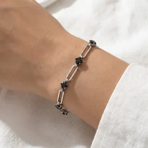 Close-up detail of silver paperclip bracelet with black rhombus zircon stones on wrist