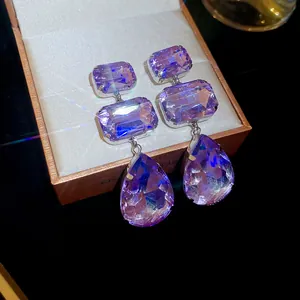 Detail showing the sparkle of purple crystal teardrop and geometric dangle earrings