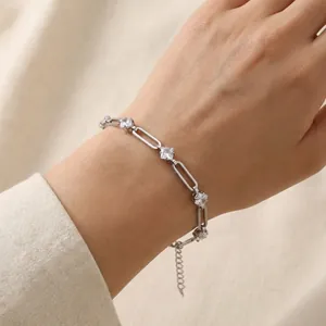 Detailed view of a silver stainless steel paperclip bracelet with zircon stones on a wrist.