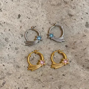 Detailansicht von silbernen und goldenen Stern-Creolen mit blauen und rosa Zirkonias.