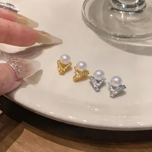 Detail of French luxury zircon and pearl stud earrings in gold and silver finish