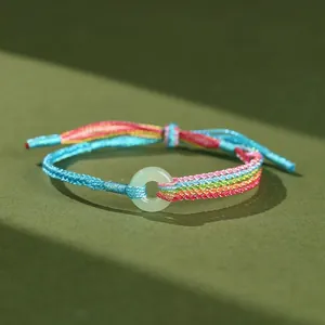 Primo piano di un bracciale intrecciato arcobaleno fatto a mano con anello in giada