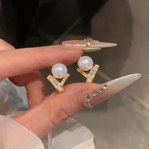 Close-up of French luxury V-shaped gold earrings with white pearls and sparkling zircons