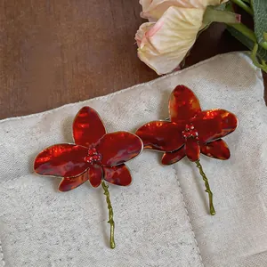 Detailed view of elegant red orchid enamel earrings with sparkling center rhinestones.