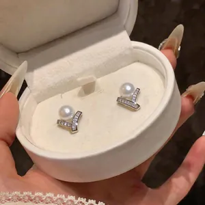 Detailed view of elegant French style zircon pearl stud earrings in a white jewelry box