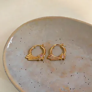 Detaillierte Nahaufnahme von eleganten goldenen Sternschnuppen-Ohrringen mit rosa Zirkon