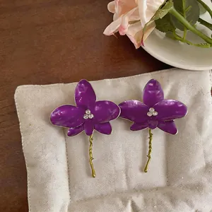 Detail view of purple enamel orchid earrings with rhinestones and golden stems.