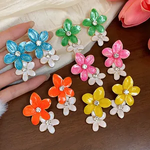 Dettaglio di orecchini a lobo a forma di fiore colorati con strass scintillanti.