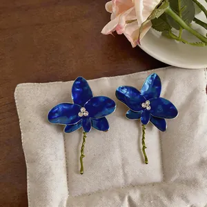Detailed macro shot of elegant blue enamel orchid earrings with sparkling rhinestones