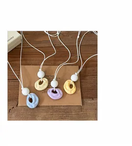 Detailed close-up showing four colorful resin irregular round necklaces on white cords