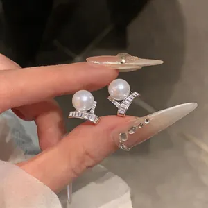 Detailed view of exquisite French luxury pearl stud earrings with zircon accents on hand