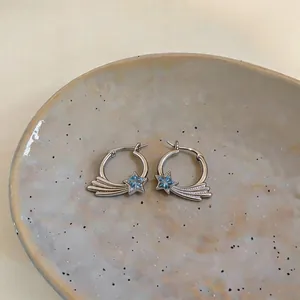 Nahaufnahme französischer Creolen mit blauem Zirkonstern-Design auf einer Keramikschale