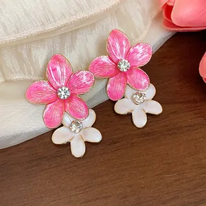 Vista dettagliata di orecchini a fiore in smalto rosa e bianco con strass scintillanti