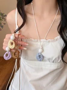 Detailed view of multi-color resin pendant necklaces with pleated texture on white cord