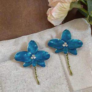Detailed view of blue oil-drop orchid earrings with sparkling rhinestone centers.