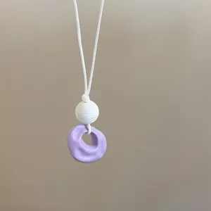 Exquisite close-up view of a purple wrinkled resin pendant on a stylish white cord