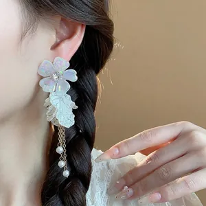 Elegant iridescent acrylic flower earrings with pearls and gold tassel on model