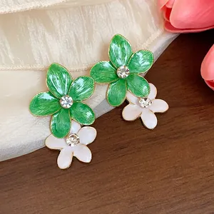 Dettaglio di orecchini a fiore in smalto verde e bianco con cristalli scintillanti