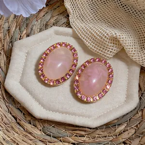 Vintage style oval pink acrylic stud earrings with sparkling crystal halo on beige pad