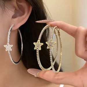 Dettaglio ravvicinato di orecchini a cerchio con stelle e strass, oro e argento
