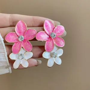 Vista dettagliata di orecchini a fiore in smalto rosa e bianco con strass scintillanti