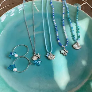 Collares de cuentas inspirados en el océano y aretes de concha en un plato turquesa