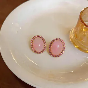 Detail shot of elegant pink oval earrings featuring a smooth acrylic stone and rhinestone halo
