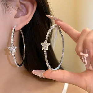 Dettaglio di orecchini a cerchio color argento con stelle di strass brillanti e cristalli