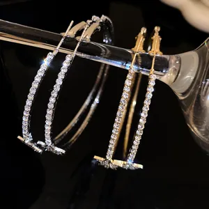 Dettaglio di orecchini a cerchio con stella in oro e argento, scintillanti di piccoli strass.