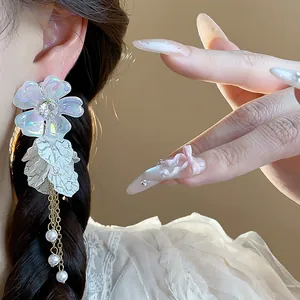 Detailed macro shot of iridescent acrylic flower earrings with pearls on a model.