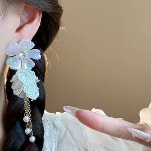 Macro view of iridescent acrylic flower earring with pearl tassels and silver needles.