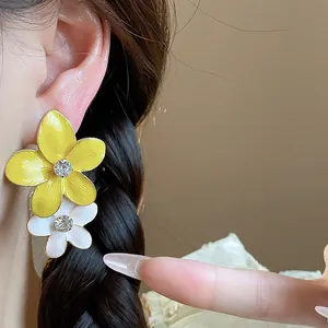 Primo piano di eleganti orecchini a doppio fiore con petali gialli e bianchi e strass