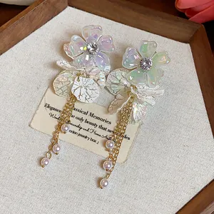 Elegant close-up of iridescent floral earrings featuring delicate pearl tassels and gold chains