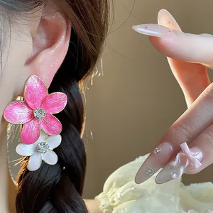 Primo piano dettagliato di orecchini a fiore in smalto rosa e bianco con strass lucenti