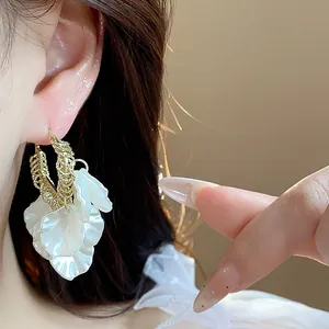 Gros plan de boucles d'oreilles pétales blancs élégantes avec texture dorée détaillée