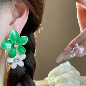 Primo piano di orecchini a fiore in smalto verde con strass centrali scintillanti