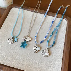 Detalle de collares de cuentas azules estilo playa con colgantes de conchas y estrellas de mar