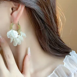 Détail de boucles d'oreilles pétales blanches élégantes, soulignant les textures délicates