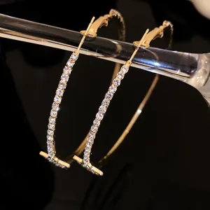 Primo piano di orecchini a cerchio dorati con barra a T e strass scintillanti