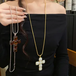 Elegant resin cross pendant necklace in white and amber colors with sleek metal chains