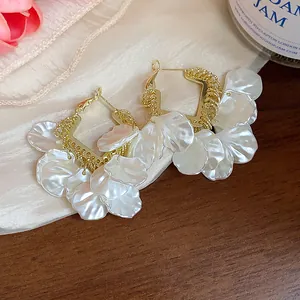 Gros plan de boucles d'oreilles créoles dorées de style français avec pétales nacrés