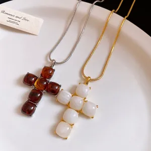 Minimalist resin cross pendant necklaces in amber and white finishes with snake chains.