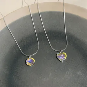 Detail view of iridescent heart and round crystal pendants on thin silver chains