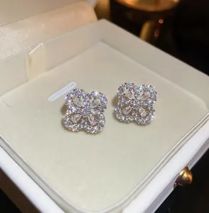 Dettaglio ravvicinato di orecchini a lobo a fiore in zirconia in una scatola regalo bianca