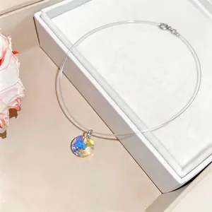 Close-up of minimalist stainless steel necklace with a round iridescent crystal pendant.